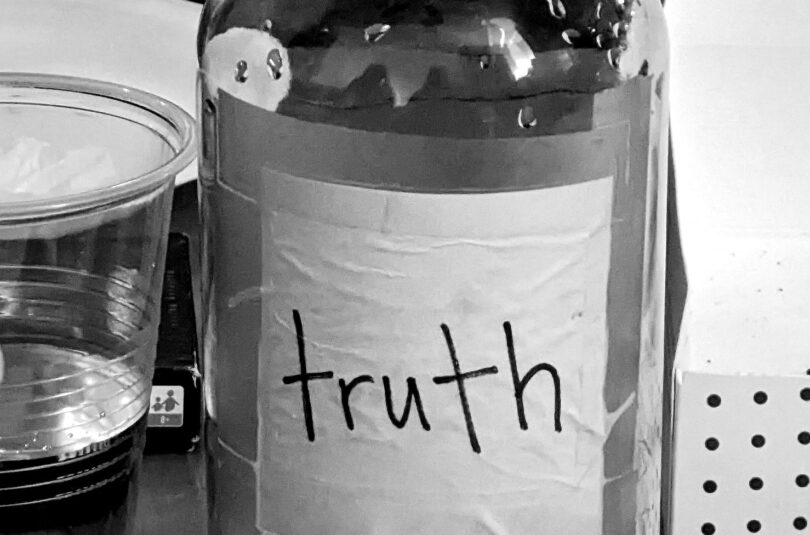 A bottle of water with the label truth, in black and white set on a table