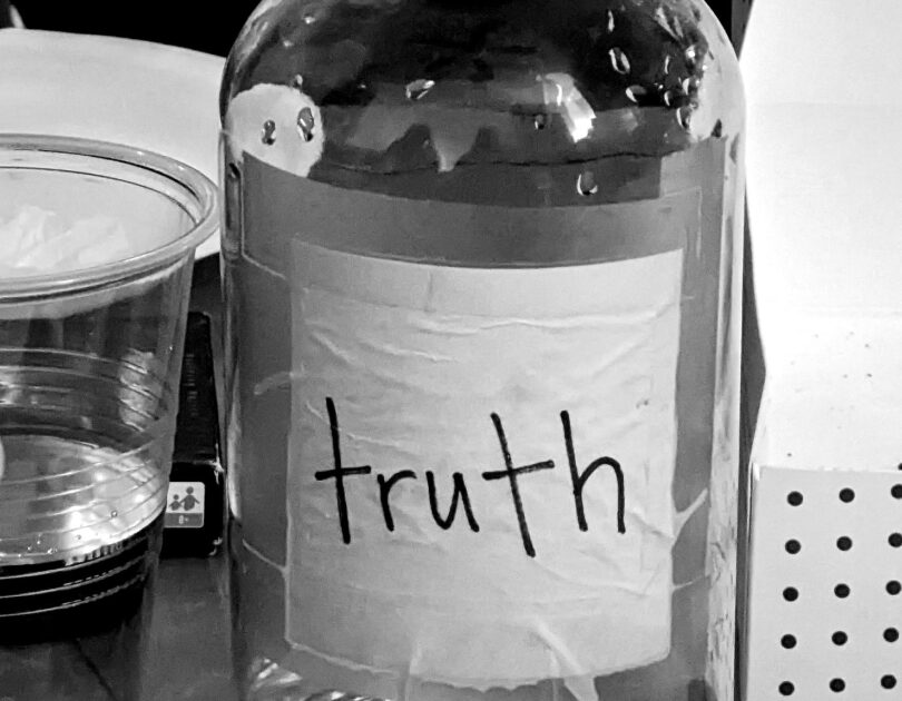 A bottle of water with the label truth, in black and white set on a table