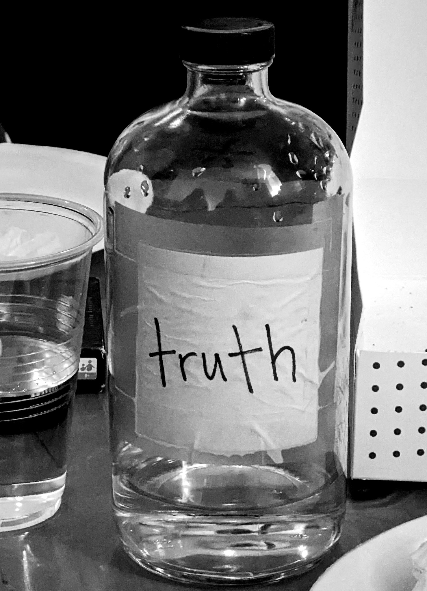 A bottle of water with the label truth, in black and white set on a table